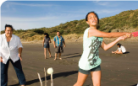 Whānau playing beach cricket